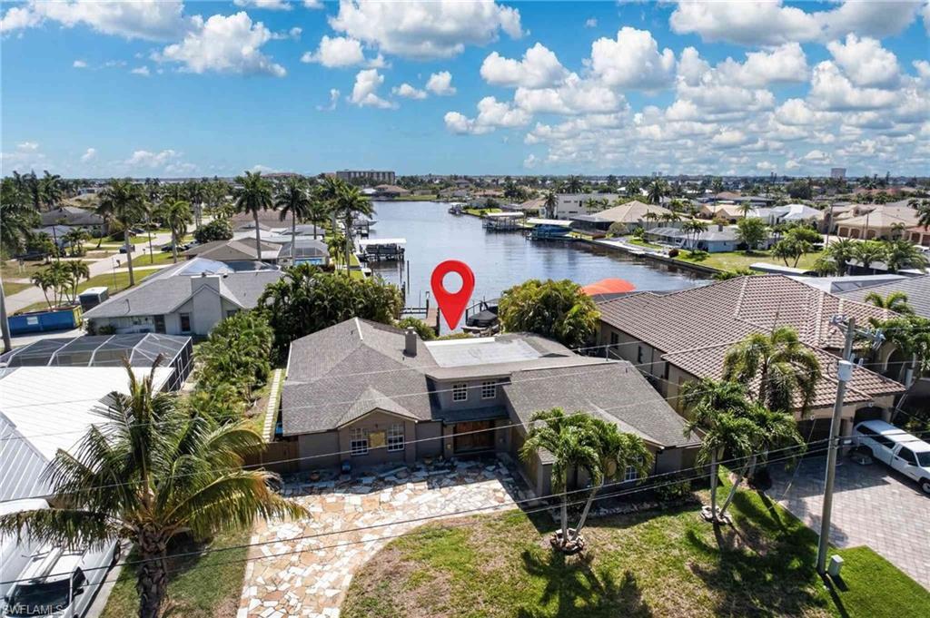 Image 4: This property features a spacious paved driveway, a well-maintained lawn, and mature palm trees