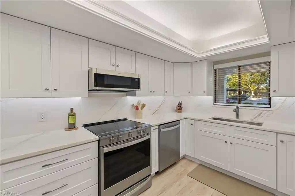 Image 1: Kitchen featuring white cabinetry, sink, light wood-type flooring, and appliances with stainless steel finishes