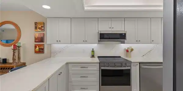 Image 2: Kitchen with white cabinets, decorative backsplash, light hardwood / wood-style floors, light stone counters, and stainless steel appliances