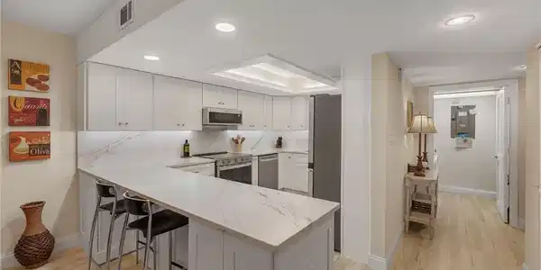 Image 3: Kitchen with kitchen peninsula, appliances with stainless steel finishes, a breakfast bar, light hardwood / wood-style floors, and white cabinetry