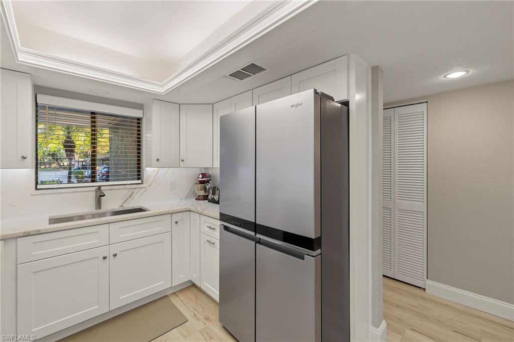 Image 4: Kitchen with white cabinets, stainless steel fridge, light hardwood / wood-style floors, and sink