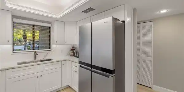 Image 4: Kitchen with white cabinets, stainless steel fridge, light hardwood / wood-style floors, and sink