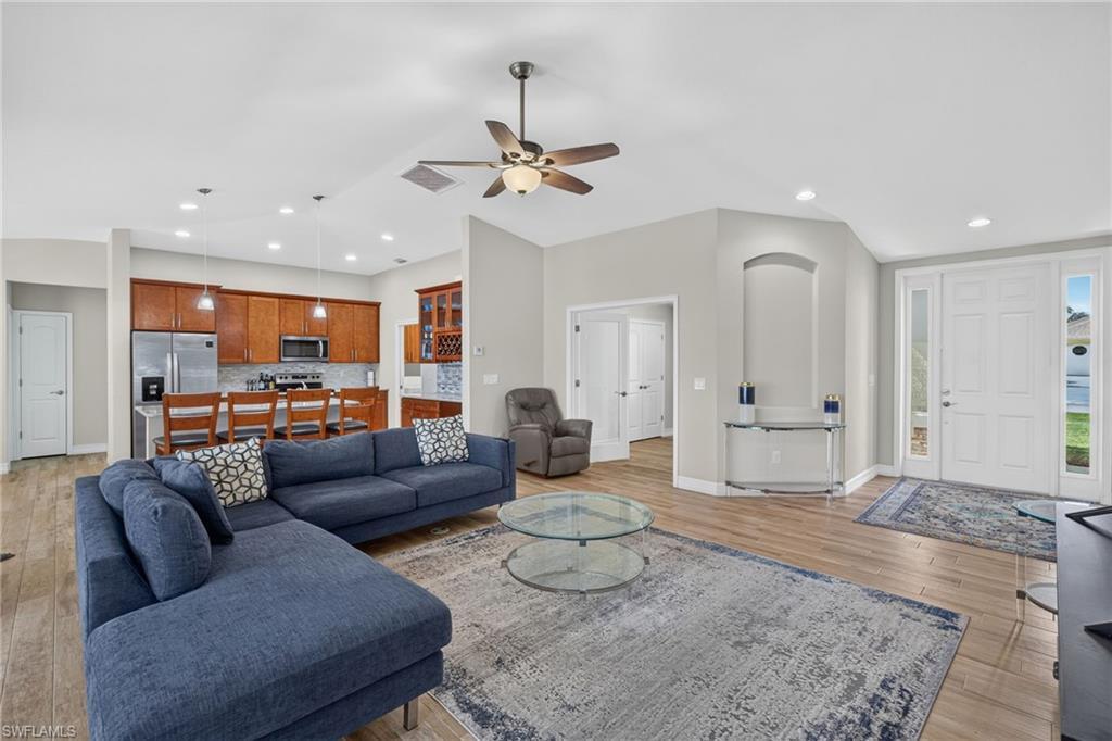 Image 4: Open-concept living area featuring wood-finish flooring, a vaulted ceiling with a ceiling fan, and recessed lighting