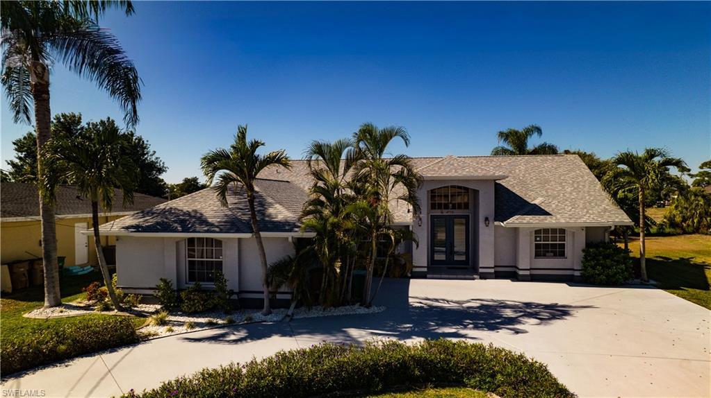 Image 2: View of front of property featuring french doors, driveway, stucco siding, and roof with shingles