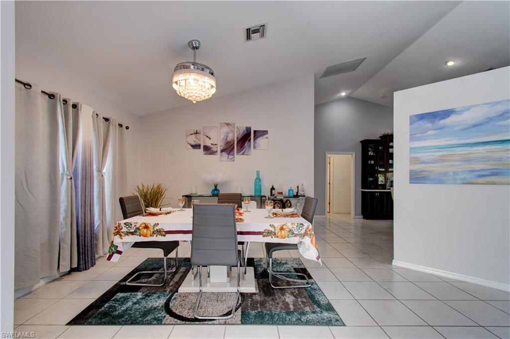 Image 4: Dining area featuring vaulted ceiling, light tile patterned flooring, recessed lighting, and a chandelier