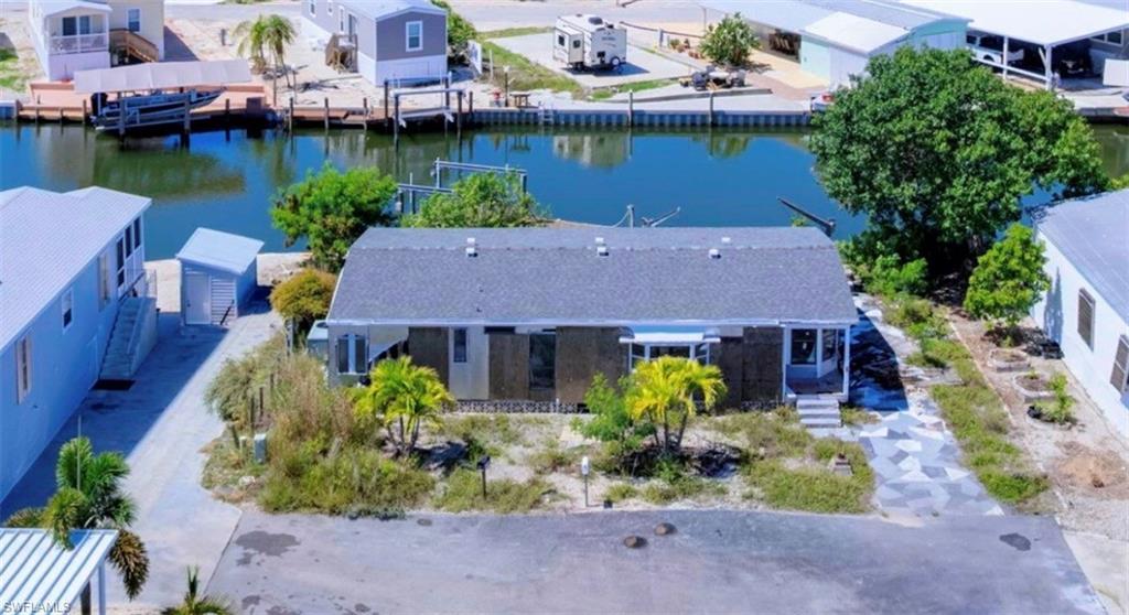 Image 2: Waterfront property featuring a private boat dock, a detached storage shed, an exterior porch, and mature palm trees