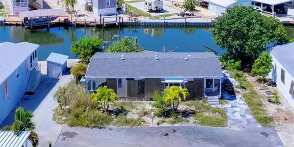 Image 2: Waterfront property featuring a private boat dock, a detached storage shed, an exterior porch, and mature palm trees