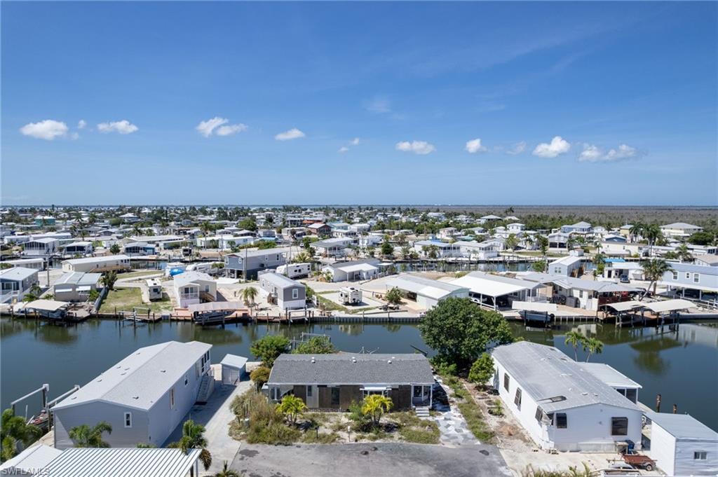 Image 3: Waterfront property featuring direct canal access, a surrounding community of residences, and a clear blue sky overhead