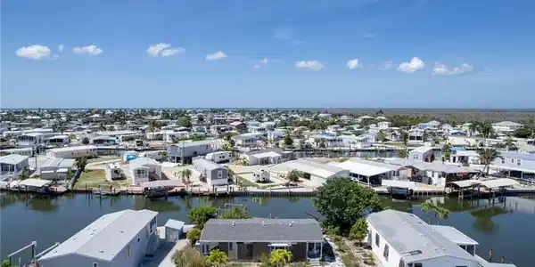 Image 3: Waterfront property featuring direct canal access, a surrounding community of residences, and a clear blue sky overhead