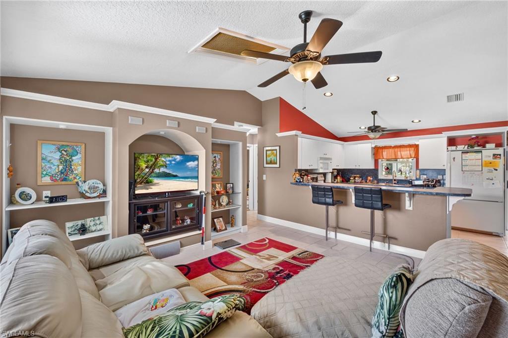 Image 2: Open-concept living space featuring vaulted ceilings, recessed lighting, and tile flooring