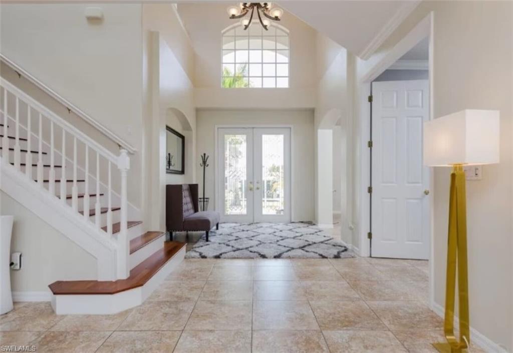 Image 3: Tiled entrance foyer featuring a high ceiling, a chandelier, and french doors