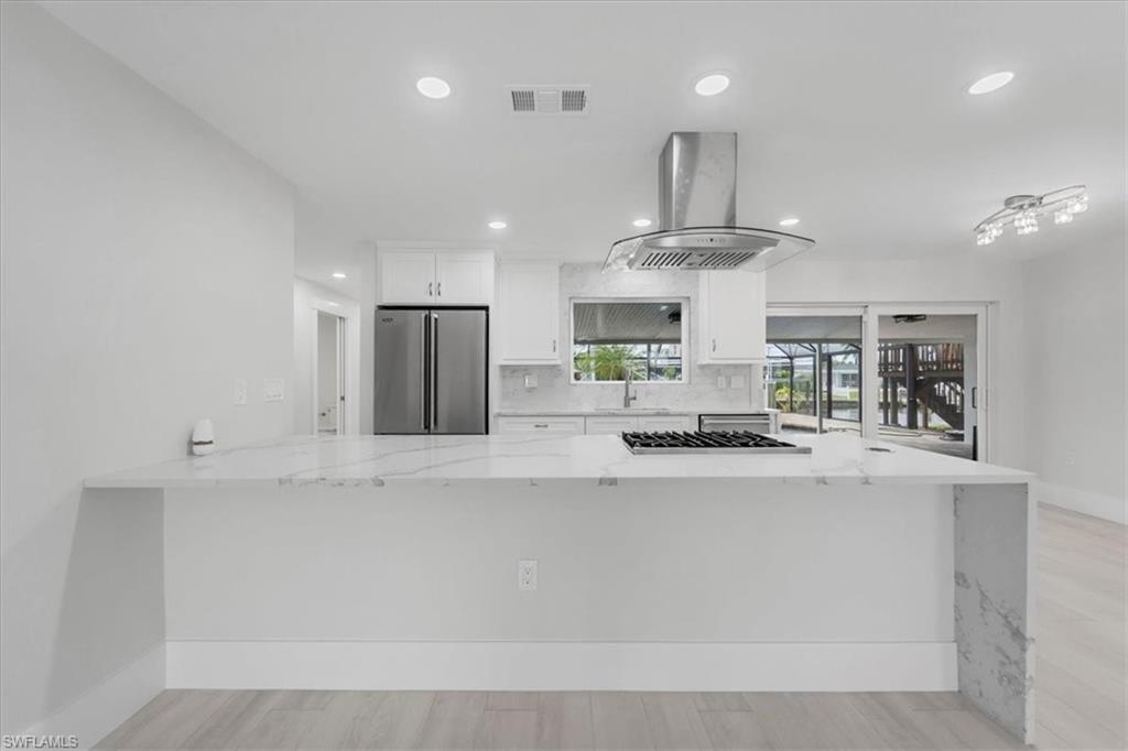 Image 4: Kitchen featuring light stone counters, white cabinets, a peninsula, appliances with stainless steel finishes, and recessed lighting