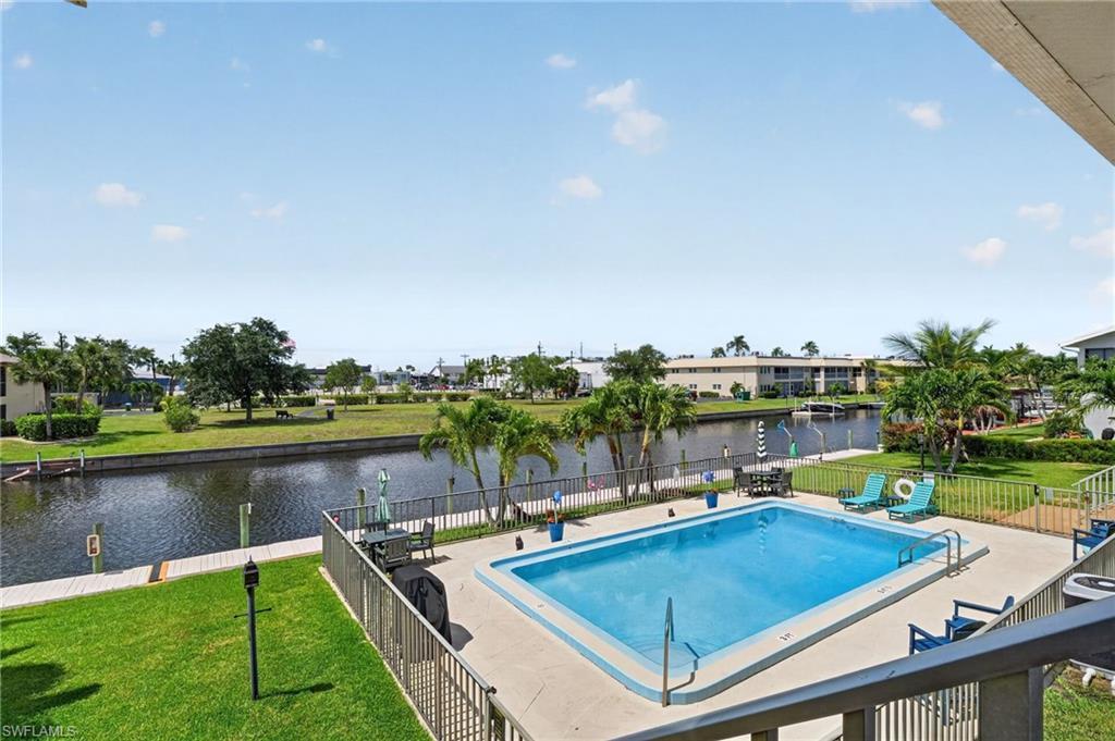 Image 3: Outdoor swimming pool with concrete decking, surrounded by a metal fence and manicured lawn