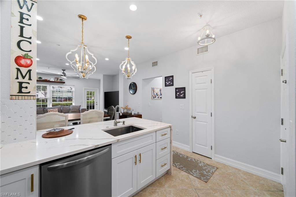 Image 3: Kitchen with dishwasher, hanging lights, light stone counters, white cabinets, and light tile patterned flooring