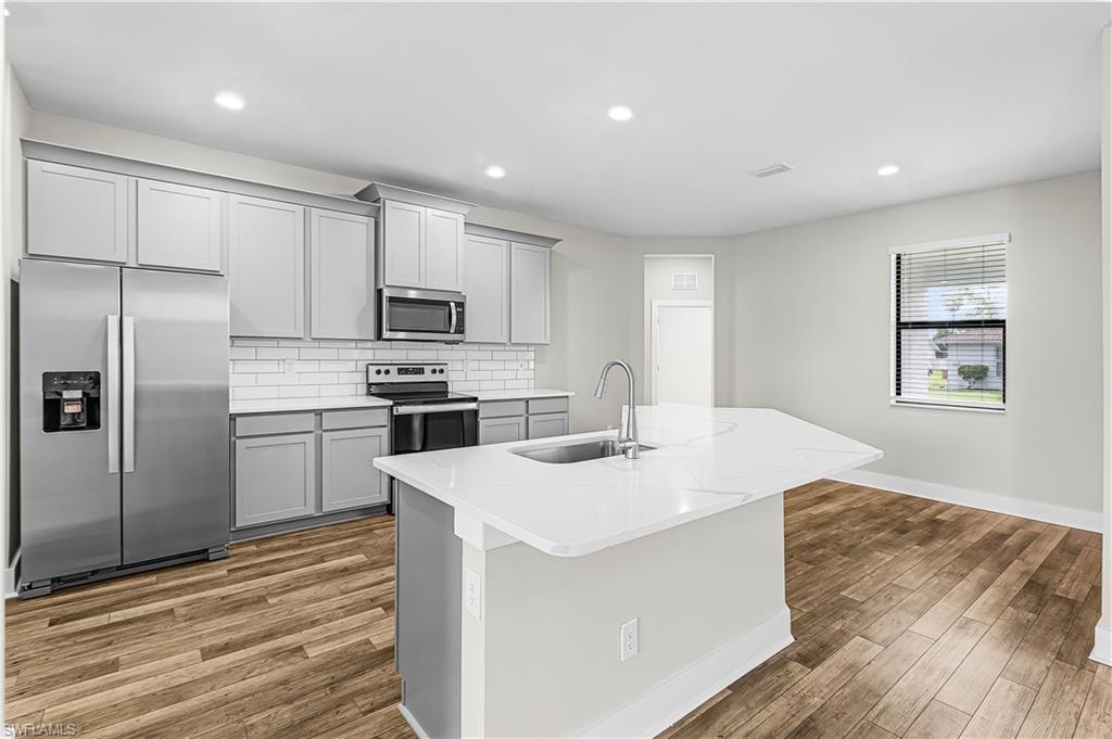 Image 4: Kitchen featuring stainless steel appliances, gray cabinets, light stone countertops, recessed lighting, and backsplash