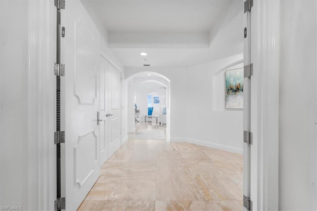 Image 4: Corridor with arched walkways, light marble finish flooring, and recessed lighting