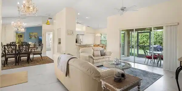 Image 3: Spacious open-concept living area featuring white tile flooring and vaulted ceilings
