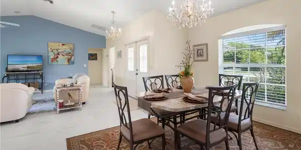 Image 4: Dining area featuring a crystal chandelier, arched window with horizontal blinds, and a built-in double-door entry