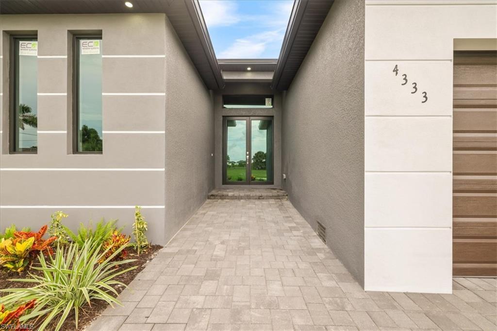 Image 2: Contemporary home with french doors, a front lawn, a shingled roof, and decorative driveway