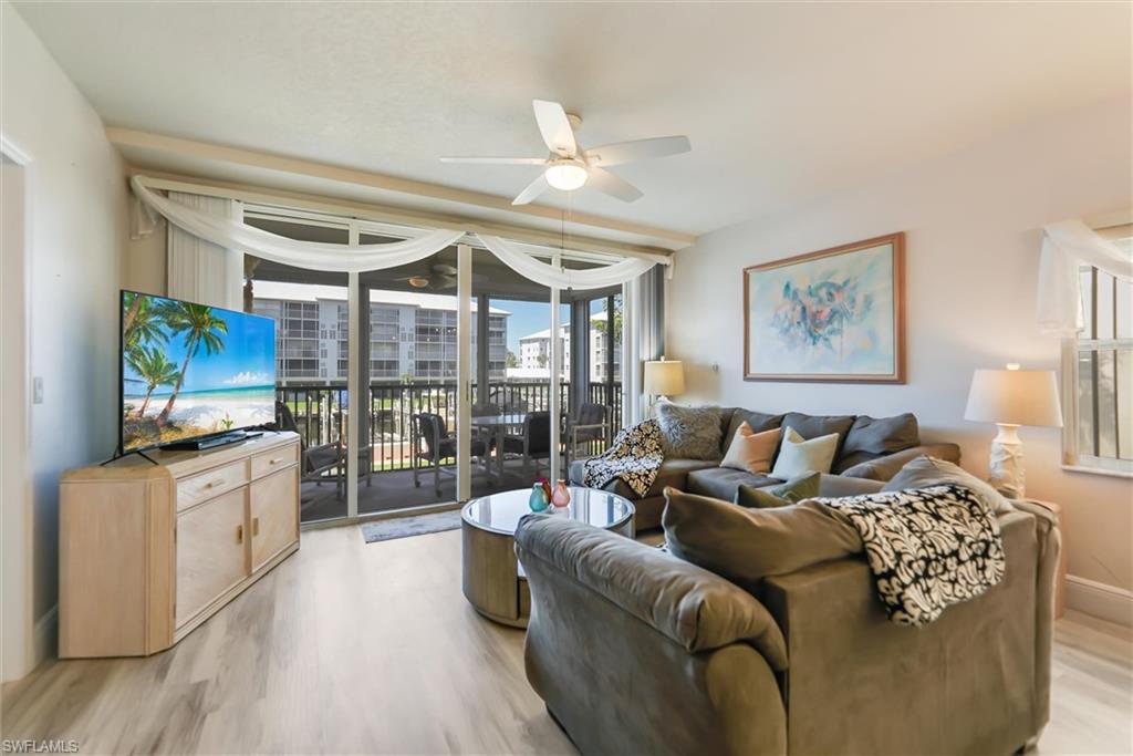 Image 2: Living room with expansive windows, ceiling fan, and light wood-type flooring