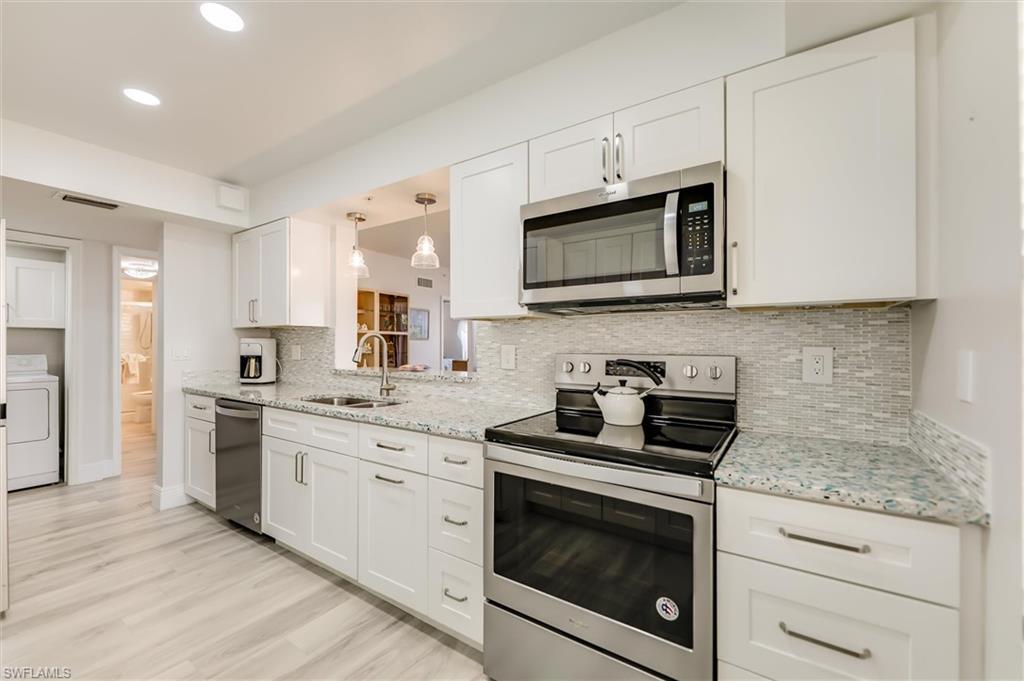 Image 4: Kitchen featuring stainless steel appliances, white cabinetry, light stone counters, and recessed lighting