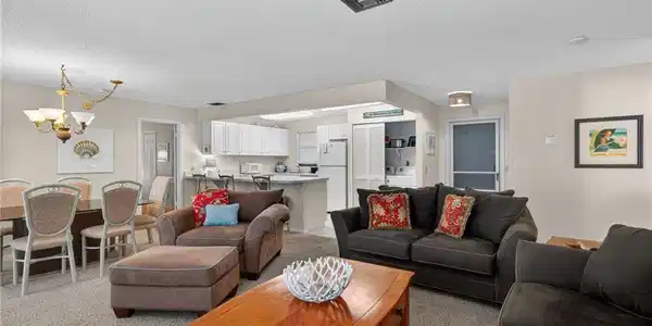 Image 4: Living room with a chandelier, a textured ceiling, and light colored carpet
