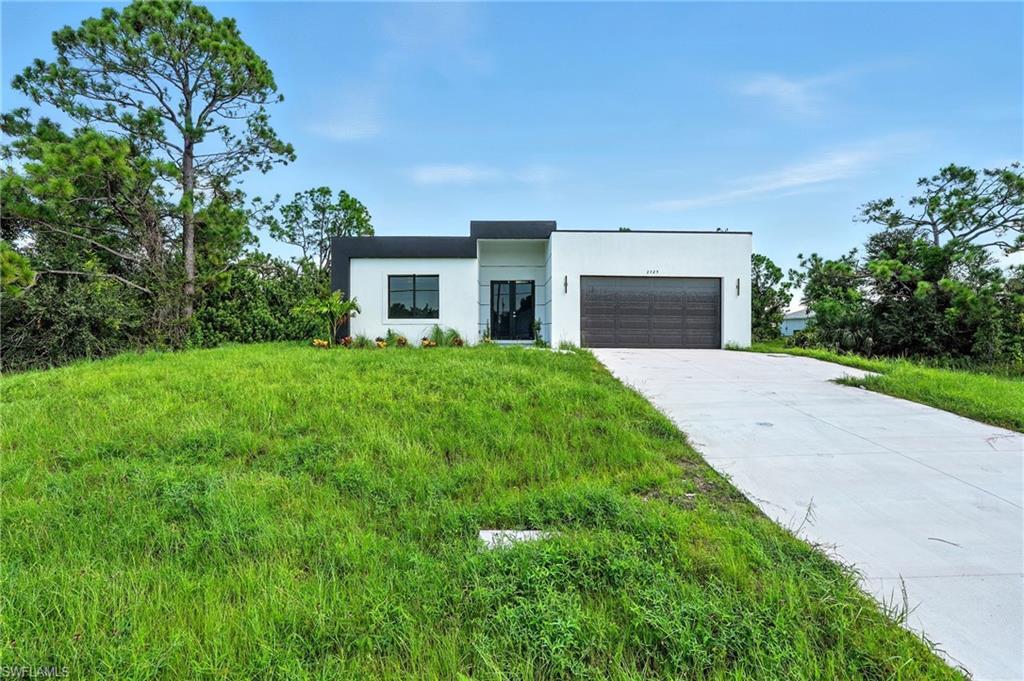 Image 2: Contemporary house featuring an attached garage, concrete driveway, stucco siding, and a front yard
