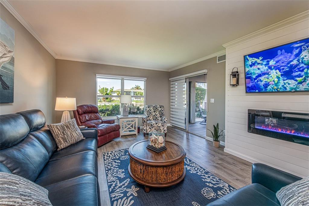 Image 1: Living room featuring a large fireplace, hardwood / wood-style flooring, and crown molding