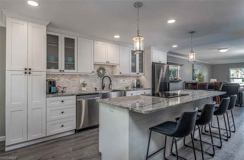 Image 3: Kitchen featuring a center island, dark wood-type flooring, white cabinets, appliances with stainless steel finishes, and decorative light fixtures