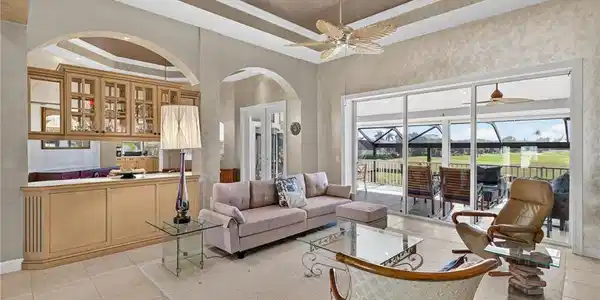 Image 4: Living room with a tray ceiling, french doors, tile patterned flooring, a premium fireplace, and ceiling fan