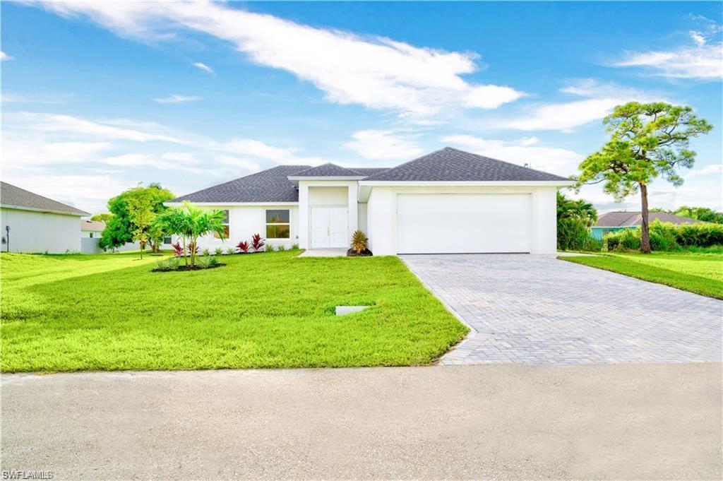 Image 1: View of front of home with a front lawn, driveway, an attached garage, roof with shingles, and stucco siding