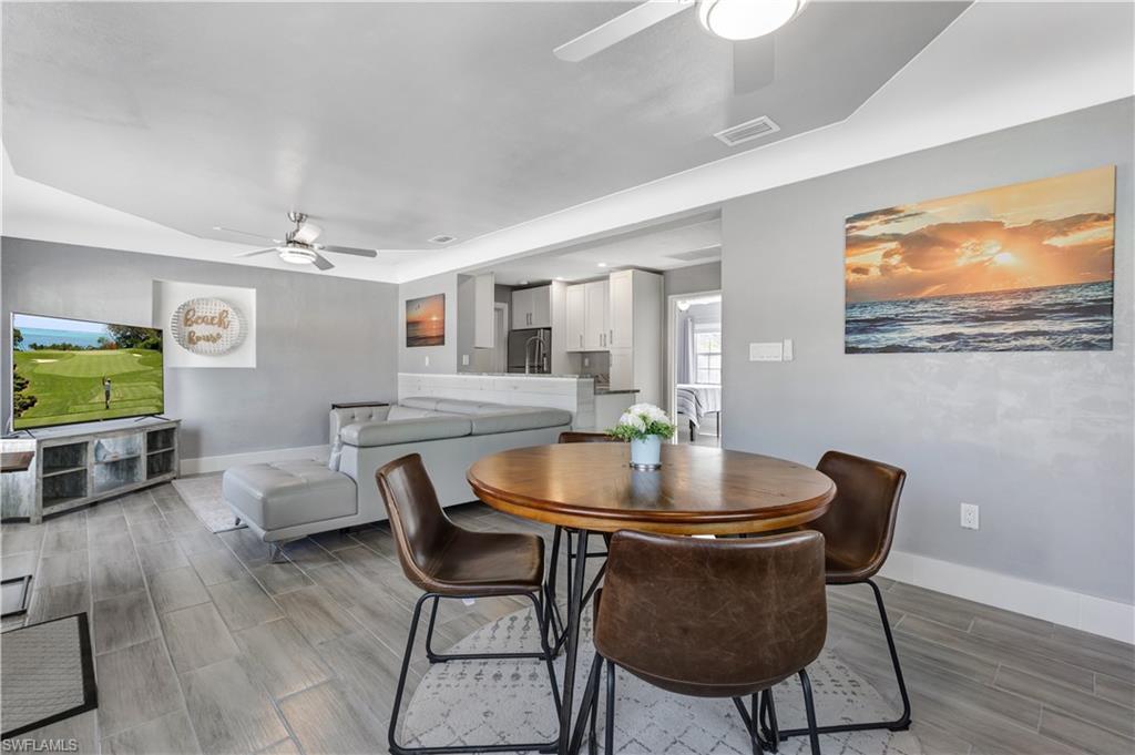 Image 3: Open-concept living space featuring wood-look tile flooring, contemporary ceiling fans, and a dining area with a round wood-finish table