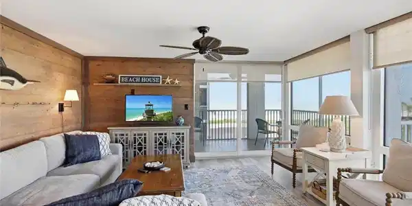 Image 4: Wood-finish accent walls, ceiling fan, wood-finish flooring, full-height windows, and glass sliding doors