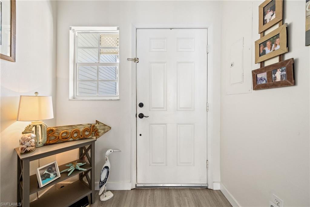 Image 3: Entryway featuring a white paneled door, light wood-finish flooring, and a window with horizontal blinds