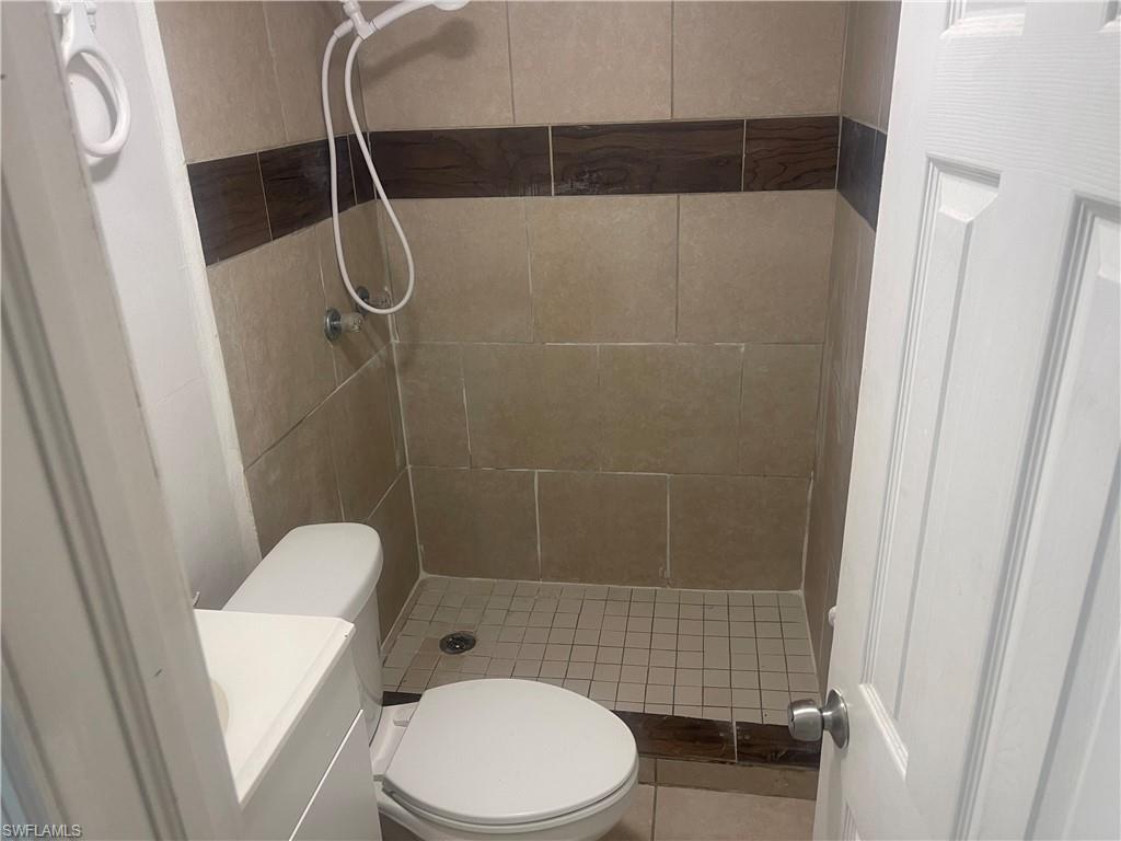 Image 2: Bathroom with a tile shower, vanity, and toilet