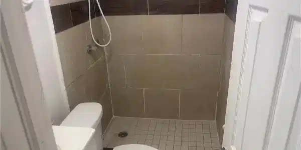 Image 2: Bathroom with a tile shower, vanity, and toilet