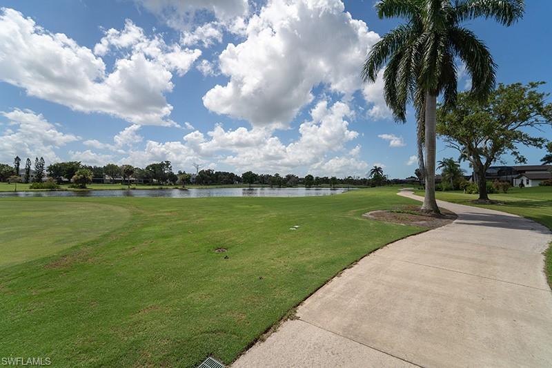 Image 2: Expansive golf course green with a curving paved pathway, mature palm trees, and a tranquil water feature