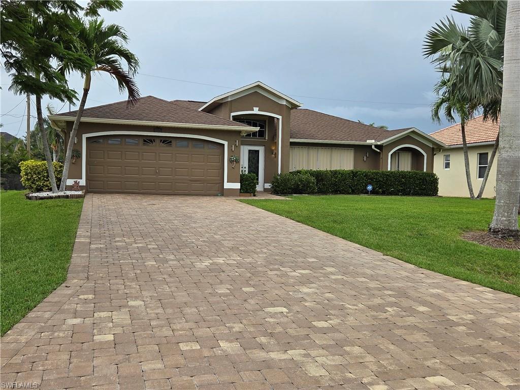 Image 1: Ranch-style home featuring a front lawn, stucco siding, paver driveway, and a 2 car garage