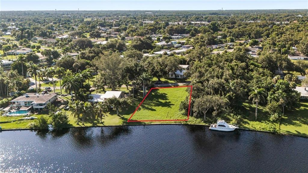 Image 1: Aerial view of property and surrounding area featuring property parcel outlined and a nearby body of water