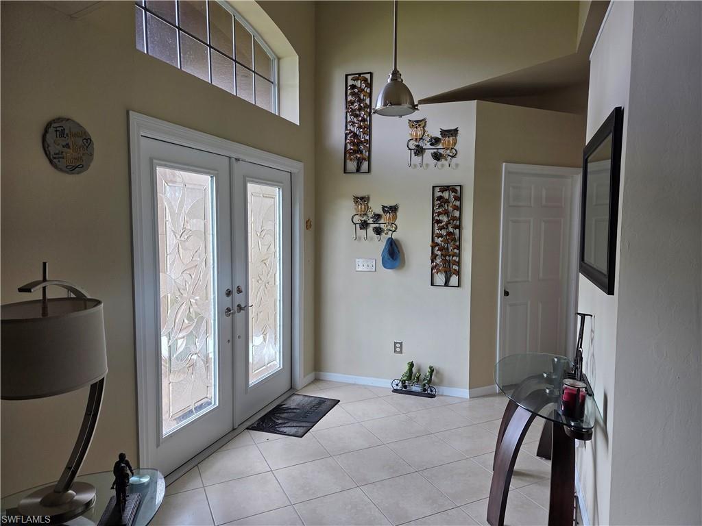 Image 2: Entrance foyer featuring french doors, light tile floors, and a towering ceiling