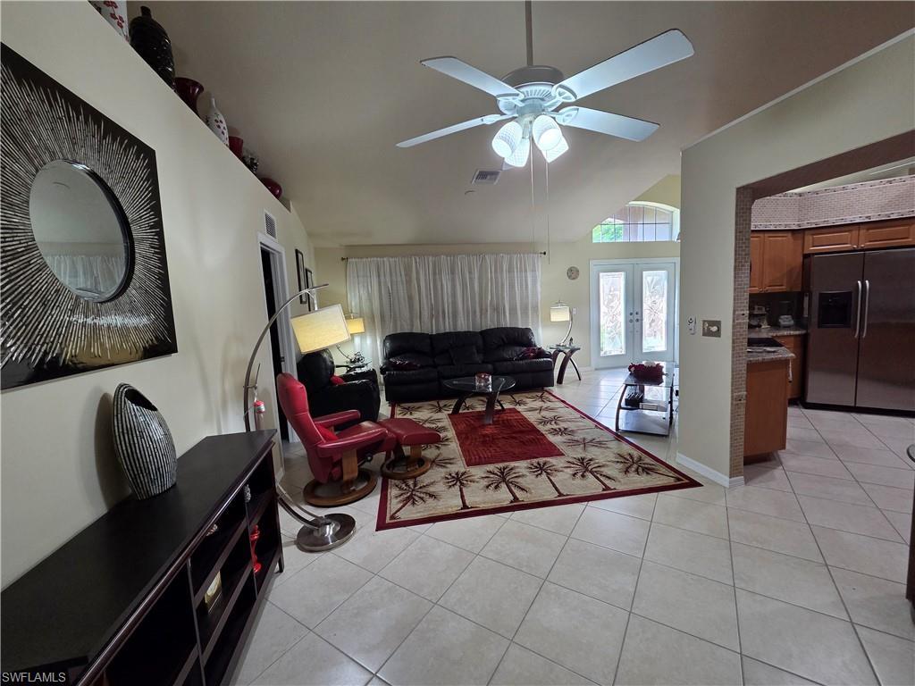 Image 3: Living room with light tile flooring, a ceiling fan, lofted ceiling