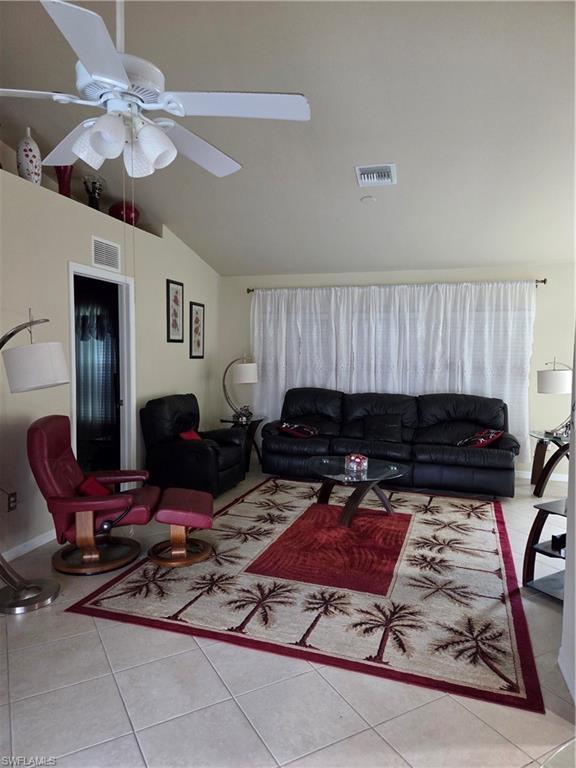 Image 4: Living area with light tile floors, vaulted ceiling, and a ceiling fan
