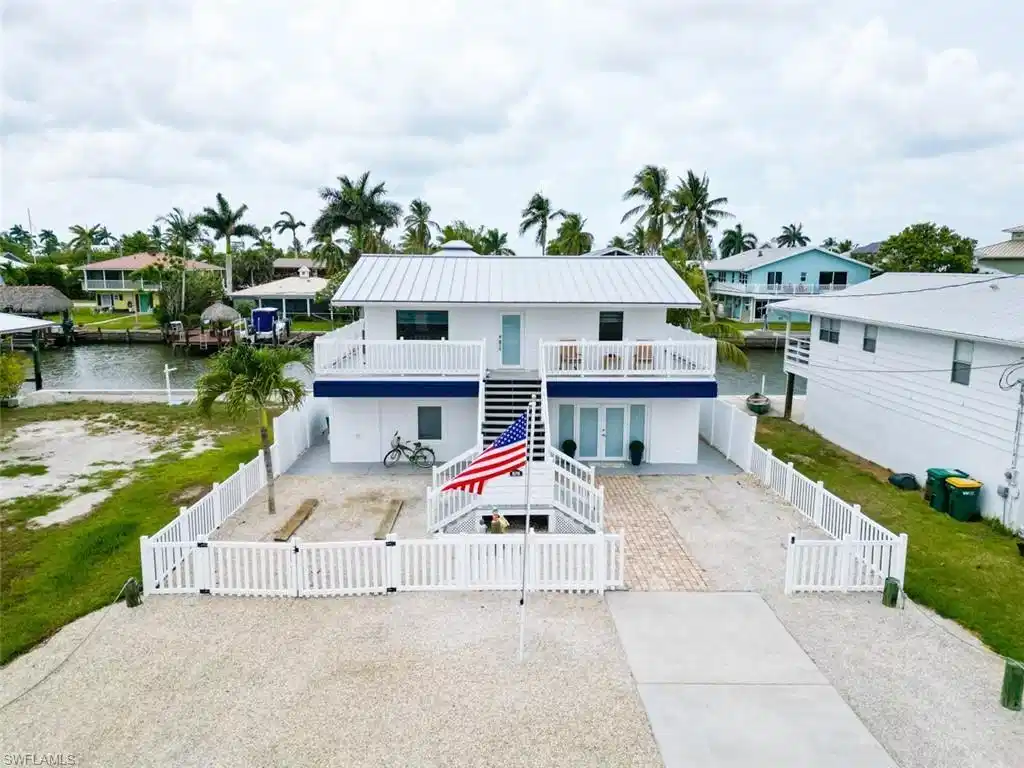 Image 1: View of front of house featuring a gate, stairway, a fenced front yard, a patio area, and a deck with water view