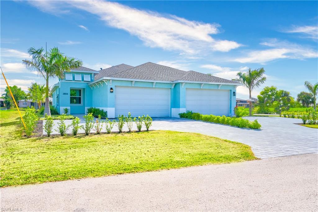 Image 2: View of front of home with decorative driveway, stucco siding, an attached garage, a shingled roof, and a front lawn