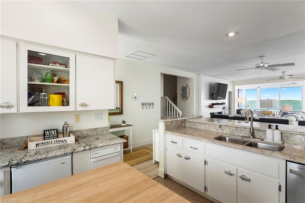 Image 4: Kitchen with white cabinets, light stone countertops, white dishwasher, a ceiling fan, and recessed lighting