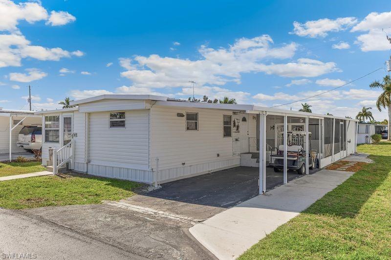 Image 2: Front of the property with a view of the carport and an additional screened-in patio/storage area in the back.