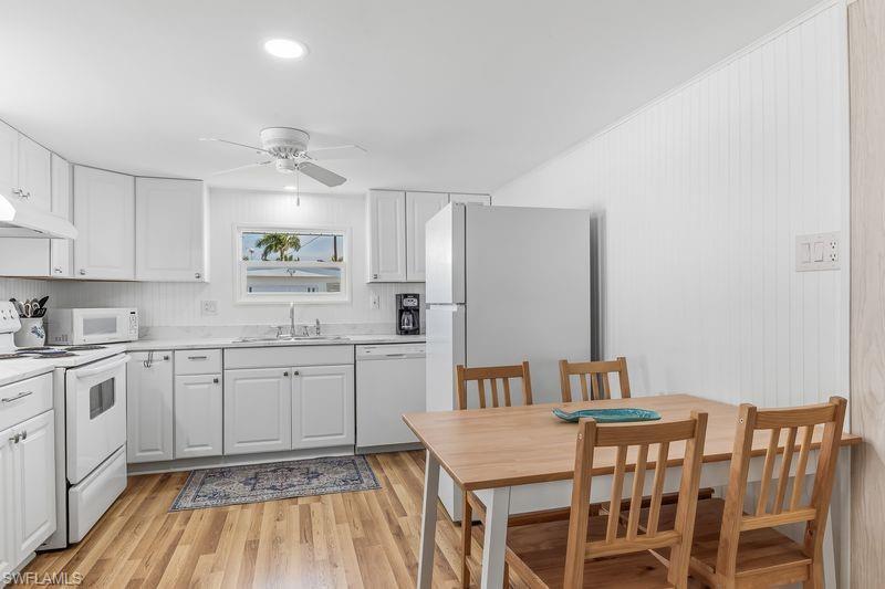 Image 3: Kitchen featuring updated white cabinetry, white appliances, wood-finish laminate flooring, recessed lighting, and a ceiling fan.