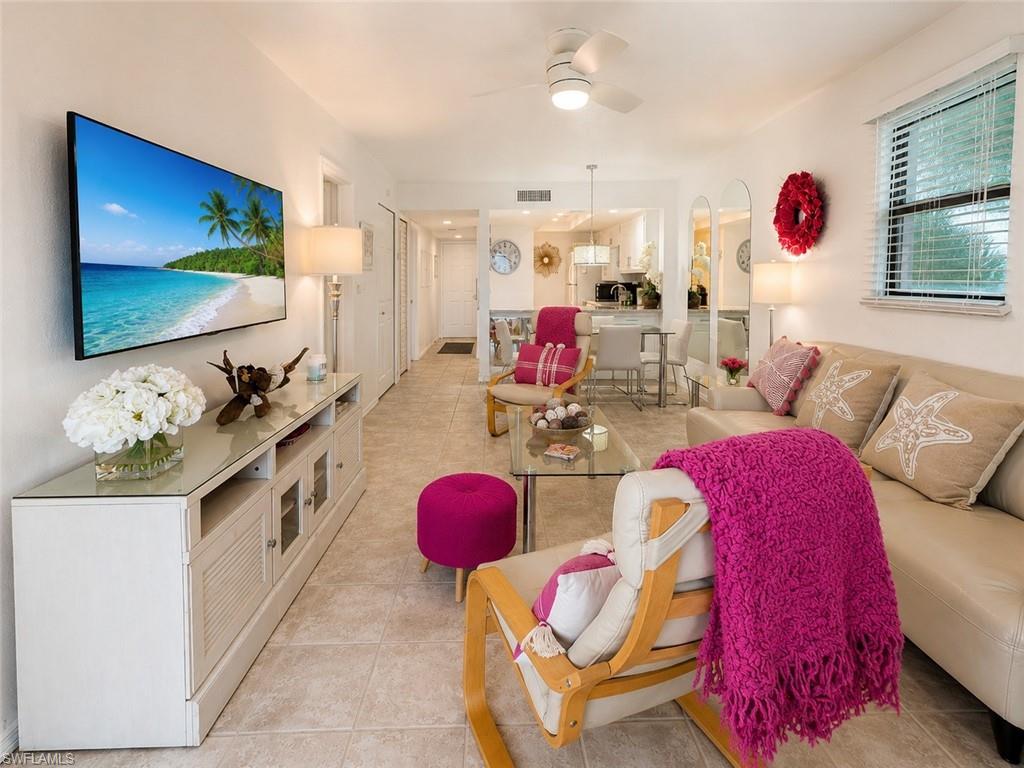 Image 1: Open-concept living space featuring neutral tile flooring, a mounted television, and a ceiling fan