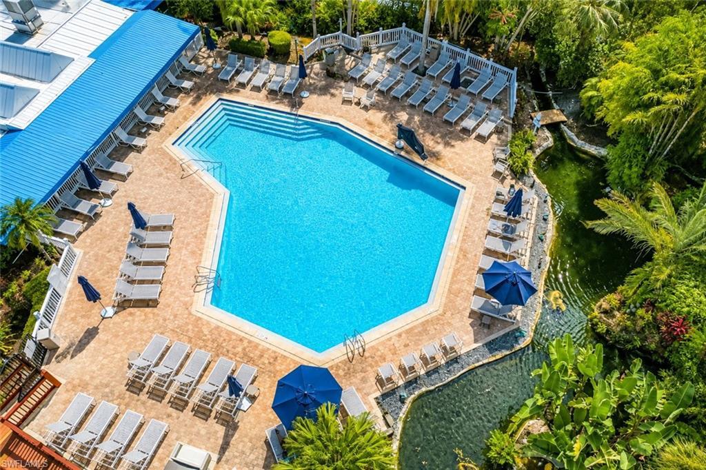 Image 3: Resort-style pool area featuring a large, geometric swimming pool with integrated steps, surrounded by extensive paver decking