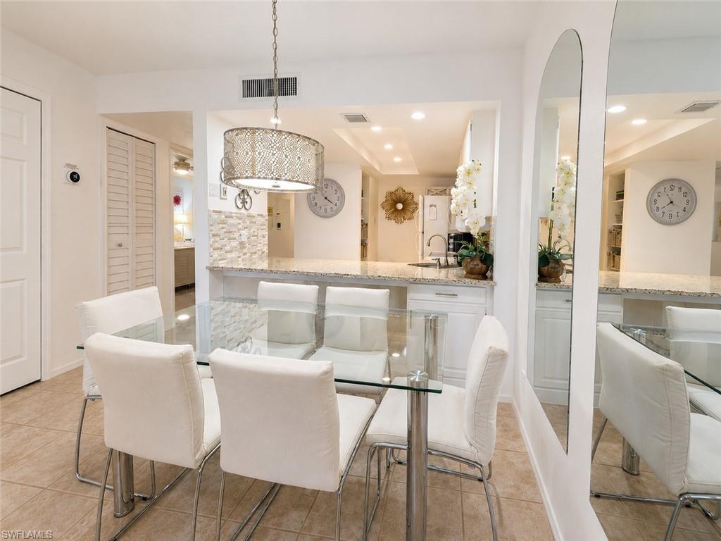 Image 4: Open-concept dining area featuring tile flooring, a decorative pendant light fixture, and a pass-through counter with a stone-finish surface